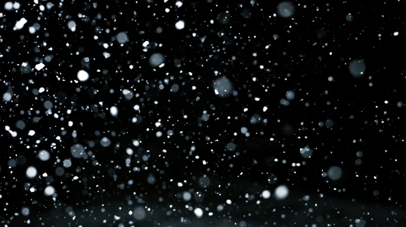 Snow falling against a dark night sky with bokeh highlights and soft focus