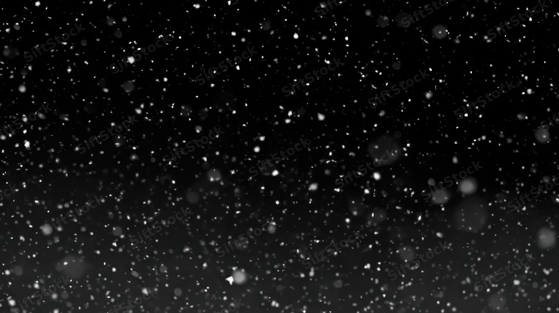 Falling snow particles against a dark night sky with bokeh effect