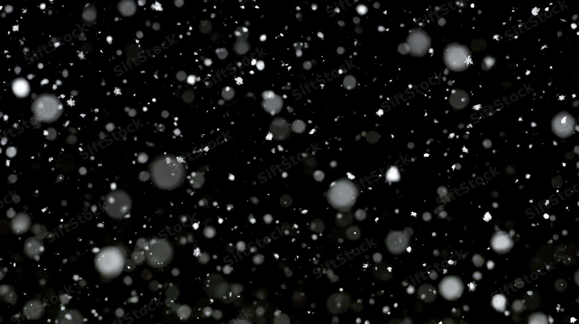 Snowflakes falling in motion against a black background with bokeh effect