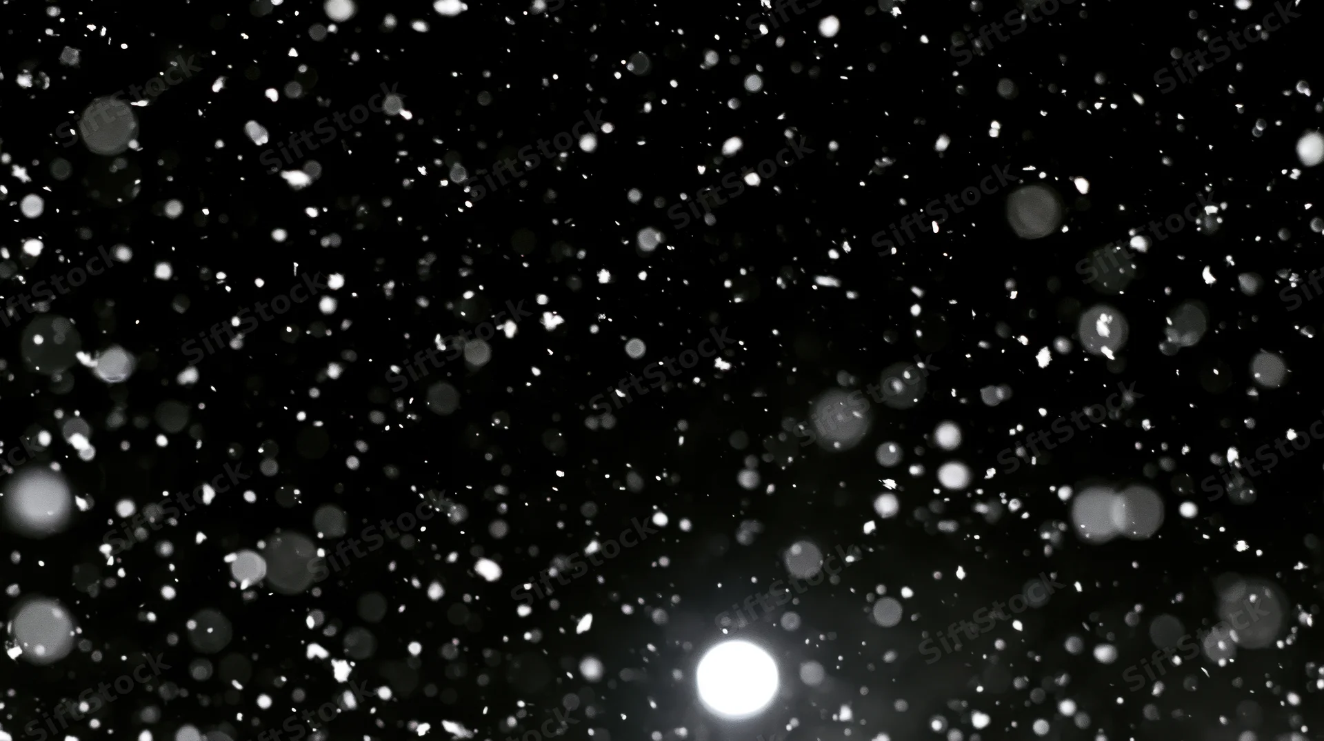 Falling snowflakes glowing softly against a dark night sky with bokeh lights