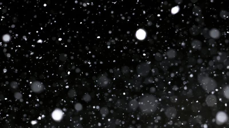 Floating white particles glowing against a dark background with bokeh effect