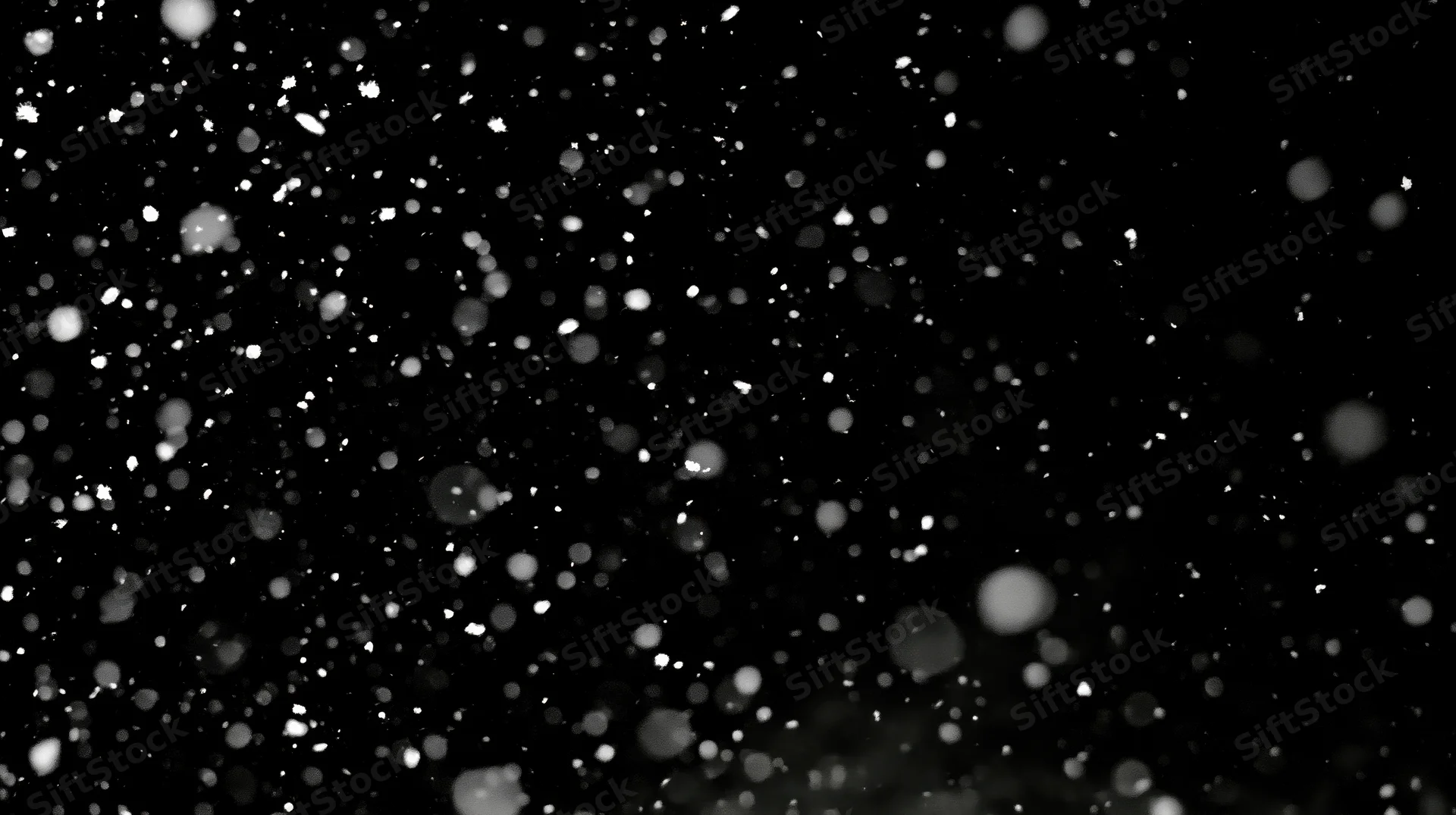 Falling snowflakes against a dark sky at night