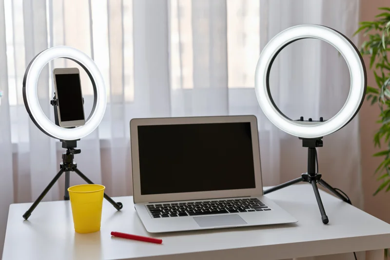 Laptop and smartphone on desk with ringlights for content creation in home office