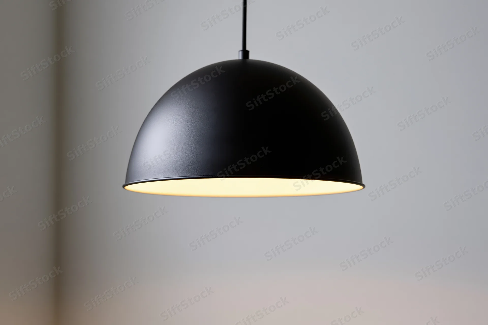 Matte black dome pendant lamp hanging from ceiling in interior space