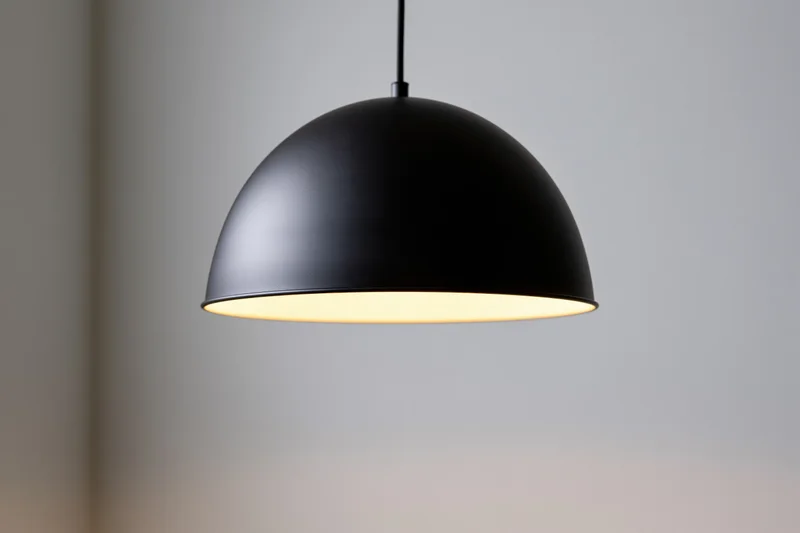 Matte black dome pendant lamp hanging from ceiling in interior space