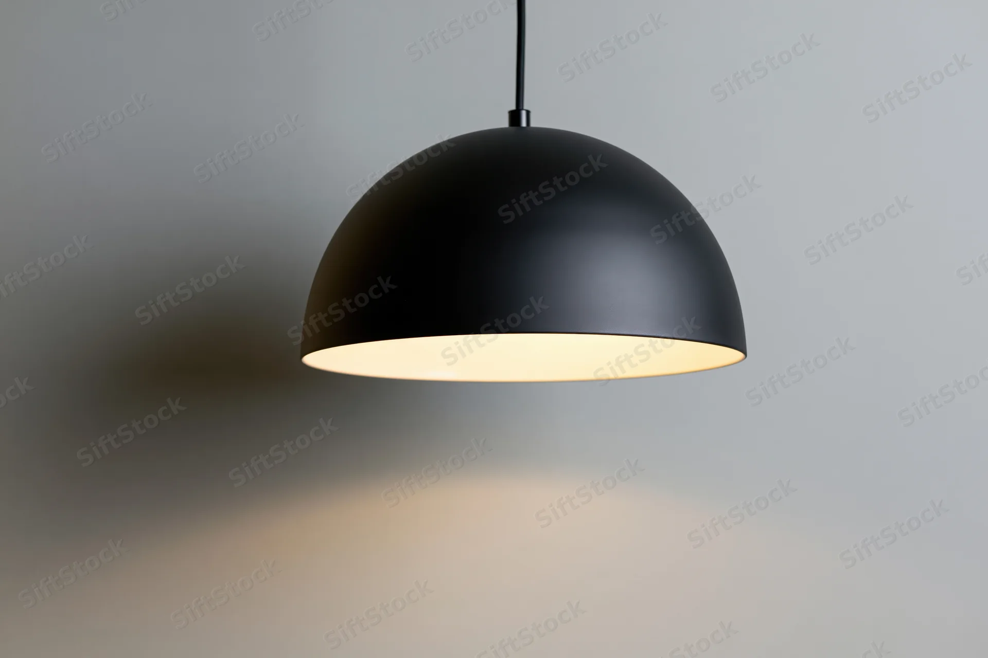 Matte black dome pendant lamp hanging from ceiling in minimalist interior