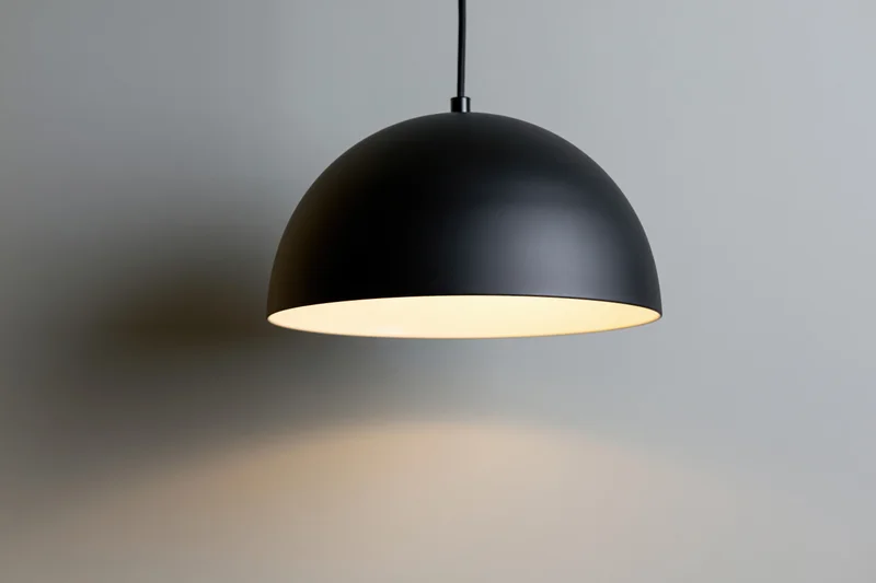 Matte black dome pendant lamp hanging from ceiling in minimalist interior