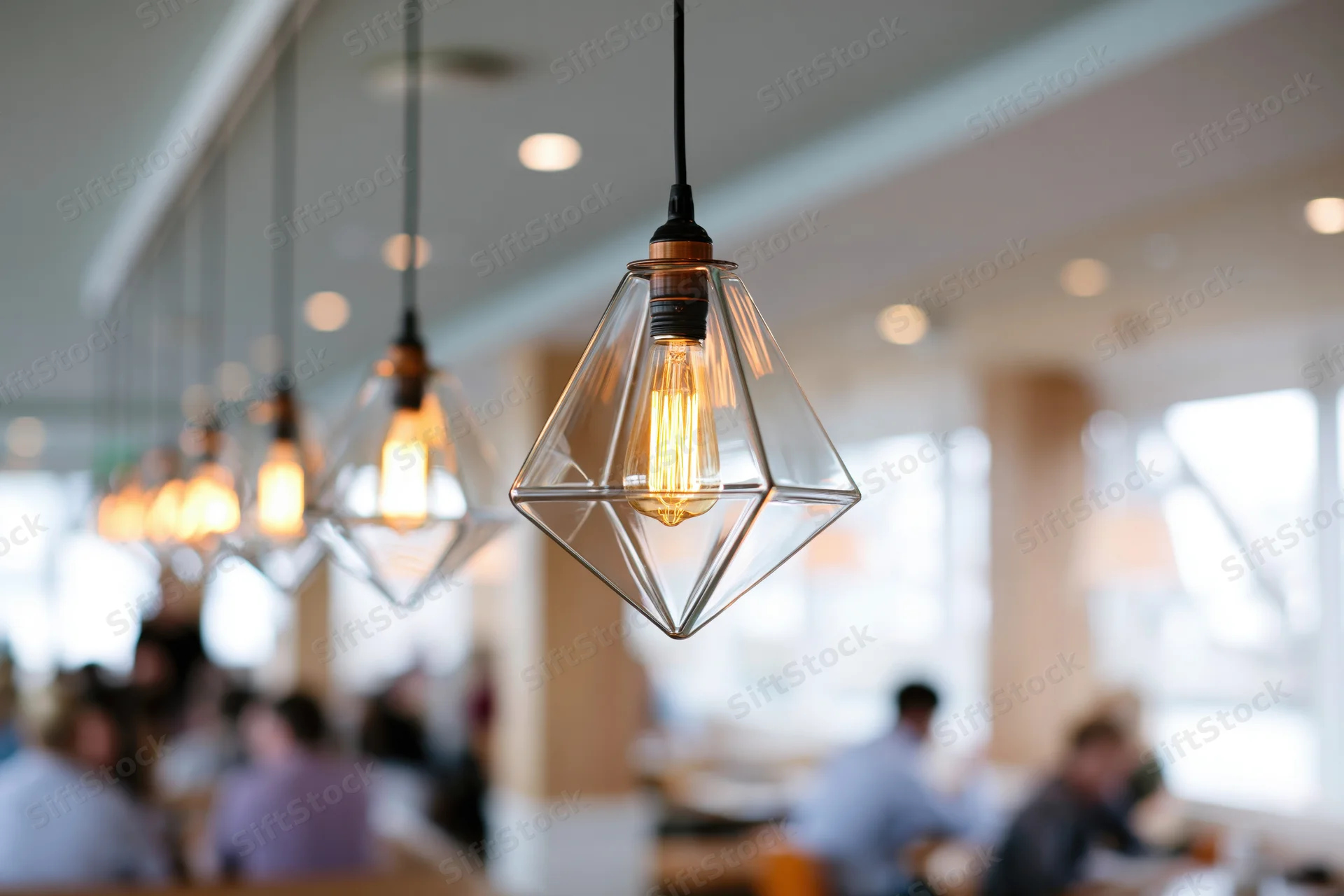 Row of geometric glass pendant lights with edison bulbs hanging in a restaurant interior