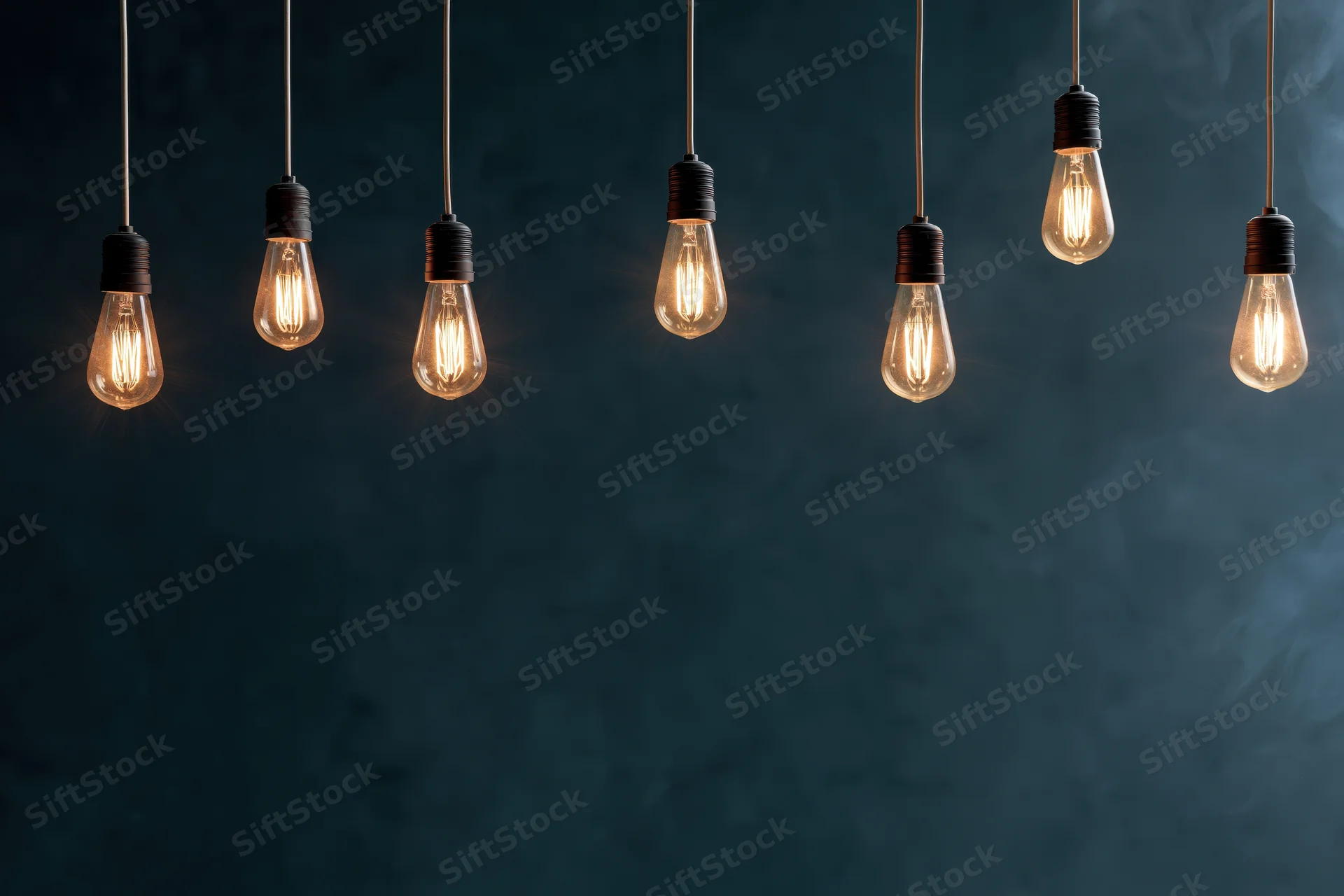 Row of hanging edison-style incandescent bulbs glowing against dark smoky background with copyspace below