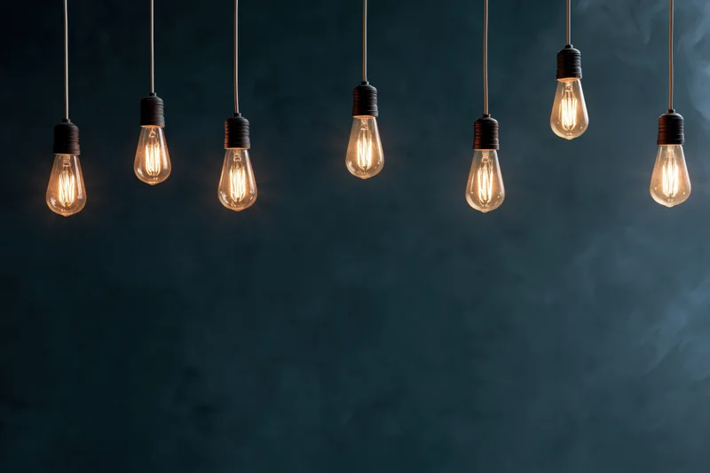 Row of hanging edison-style incandescent bulbs glowing against dark smoky background with copyspace below