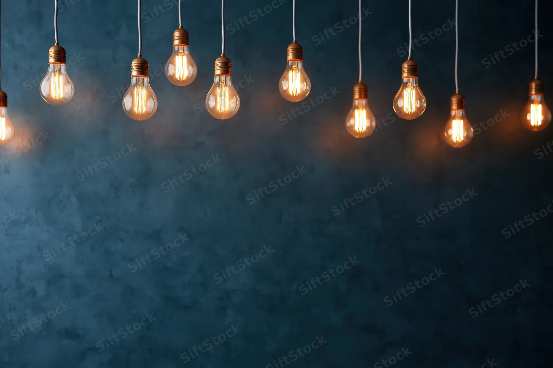 Row of glowing incandescent bulbs hanging from cords against a dark blue textured wall