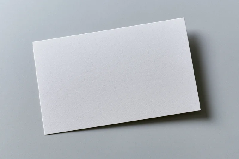 Blank white rectangular card lying flat on a gray surface