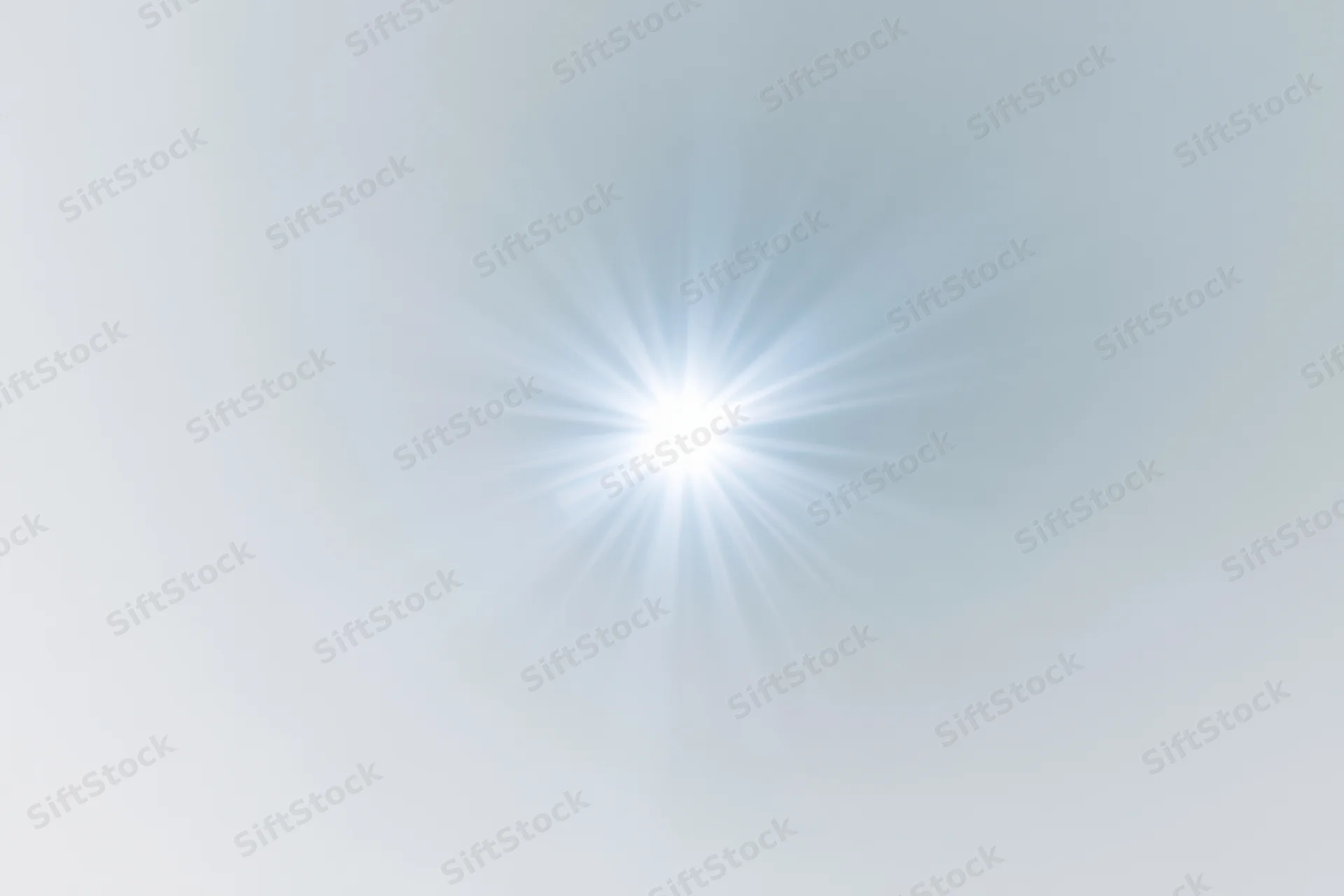 Bright lens flare starburst centered on white background with soft gradient and copyspace