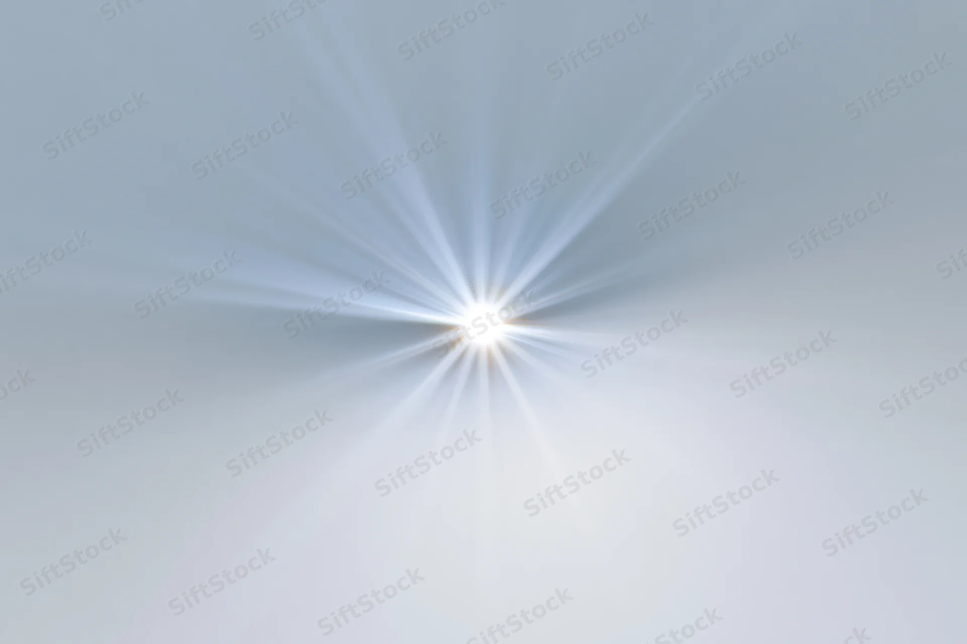 Bright lens flare starburst on white background with radiating light beams
