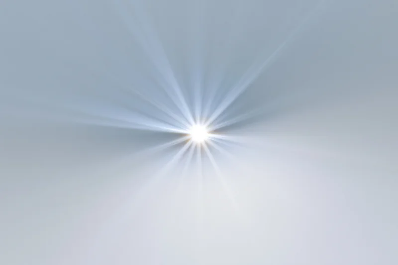 Bright lens flare starburst on white background with radiating light beams