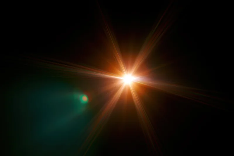 Bright point light source glowing with starburst flare against dark background