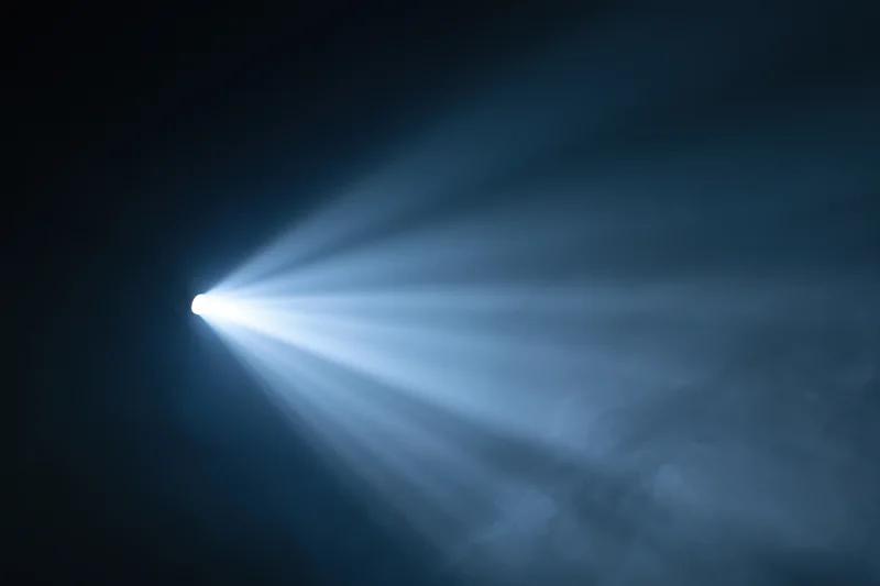 Bright spotlight beam cutting through haze and smoke in a dark space
