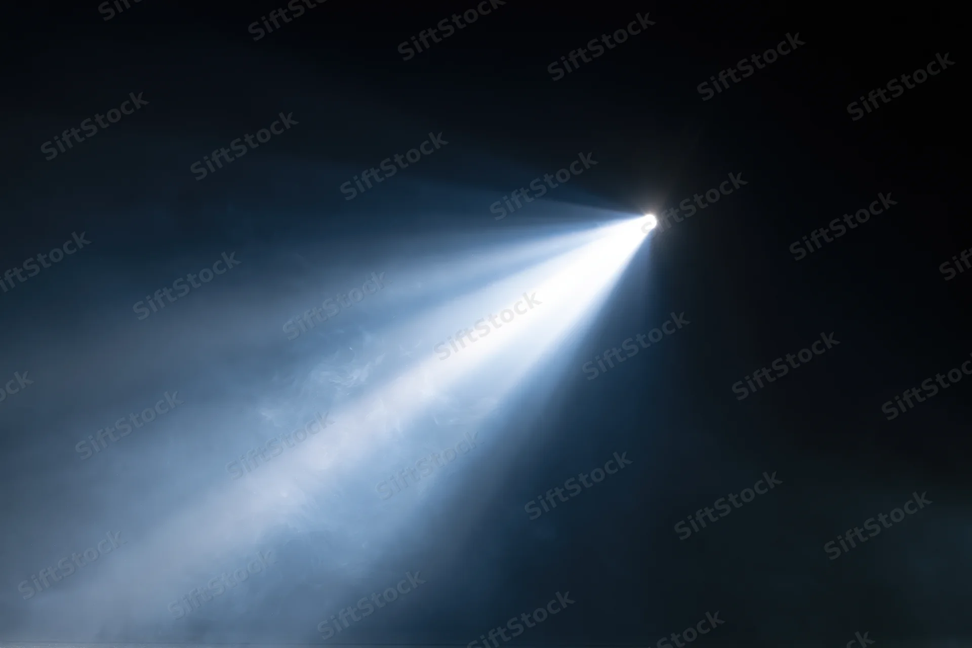 Bright spotlight beam cutting through haze in a dark theater interior