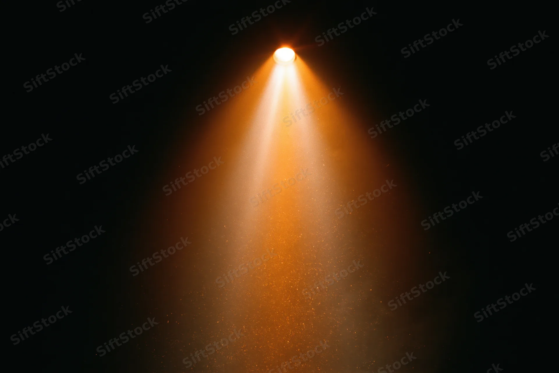 Warm amber spotlight beam shining downward in dark theater space