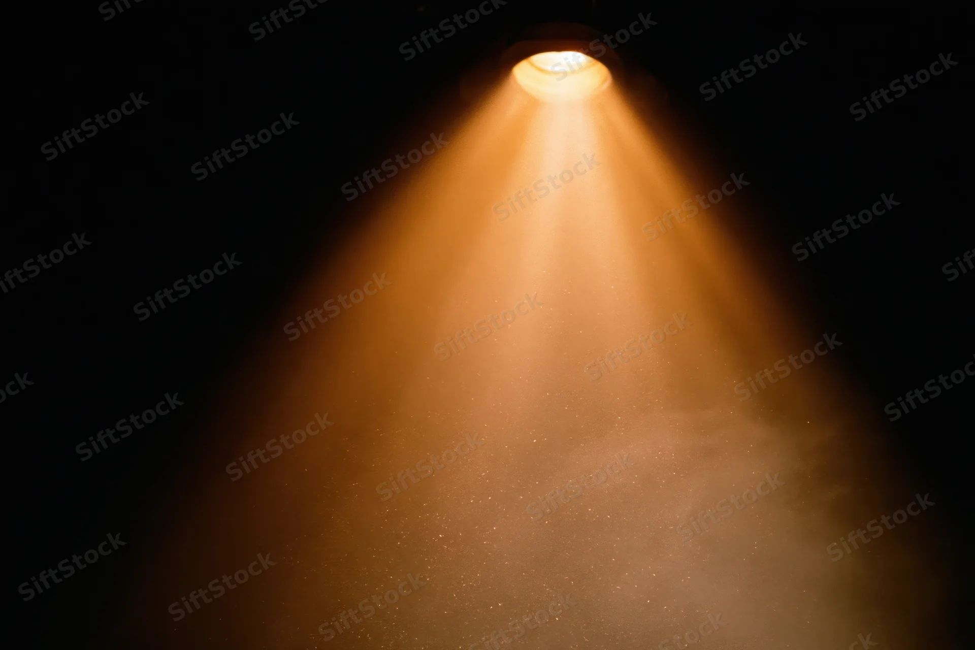 Warm amber spotlight shining downward in dark theater interior
