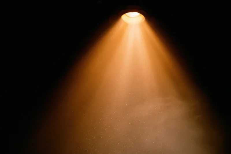 Warm amber spotlight shining downward in dark theater interior