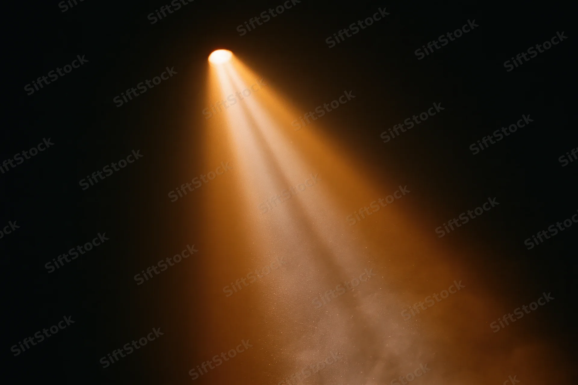 Warm amber spotlight beam shining downward through haze in dark theater space