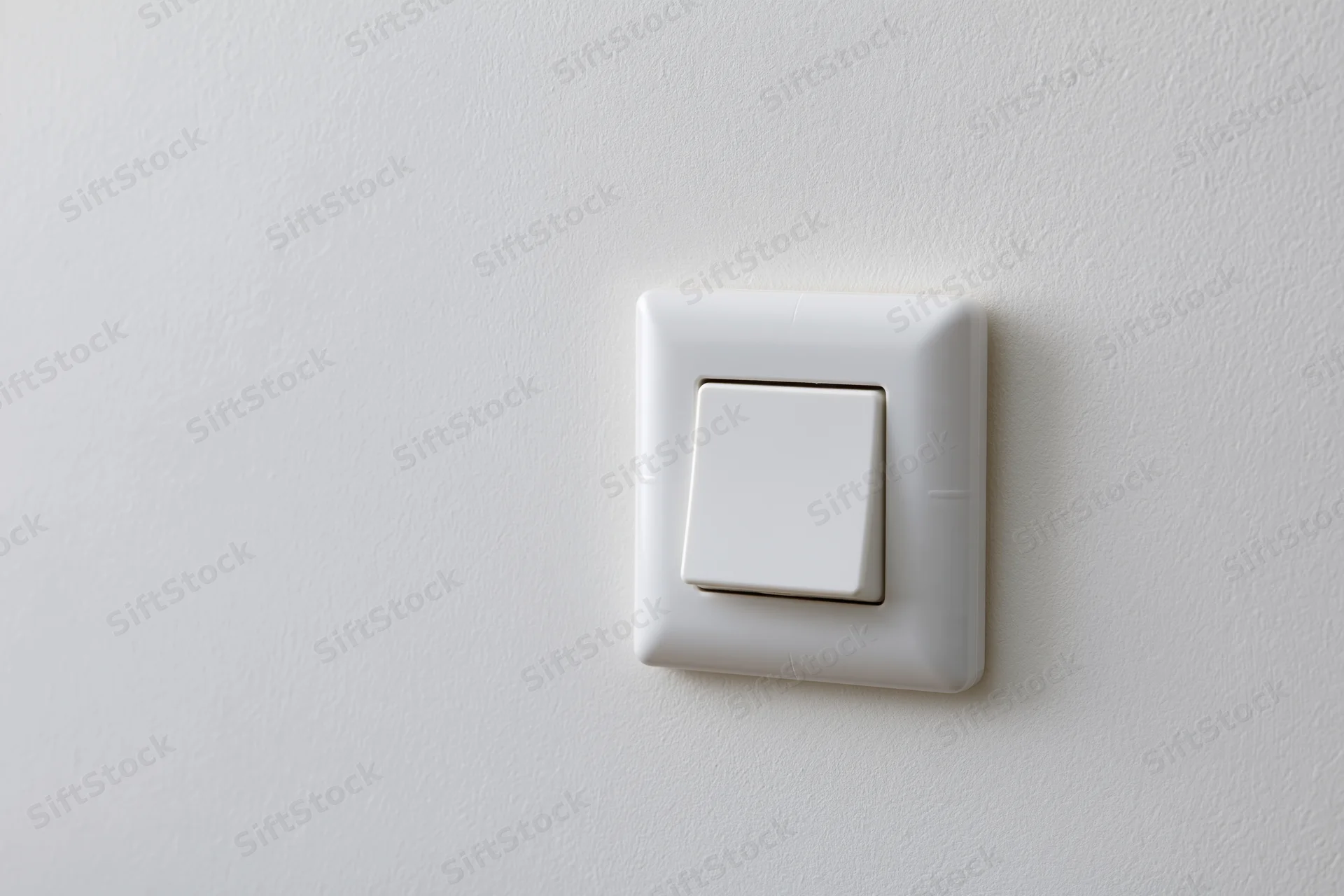 White square push-button light switch mounted on a plain wall