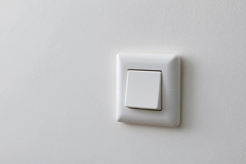 White square push-button light switch mounted on a plain wall
