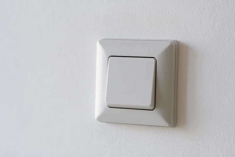 White square push-button light switch mounted on a plain wall