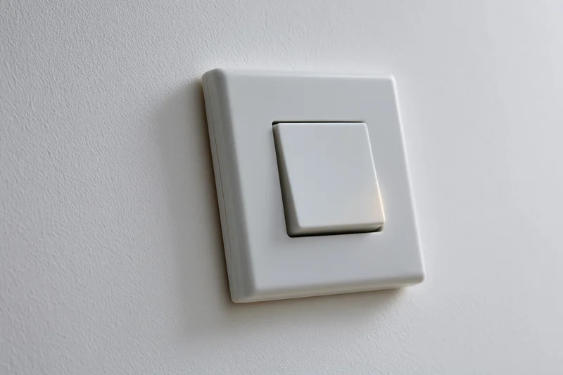 White square push-button light switch mounted flush on a textured wall interior
