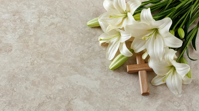 Wooden cross and white lilies arranged on a stone surface with copyspace