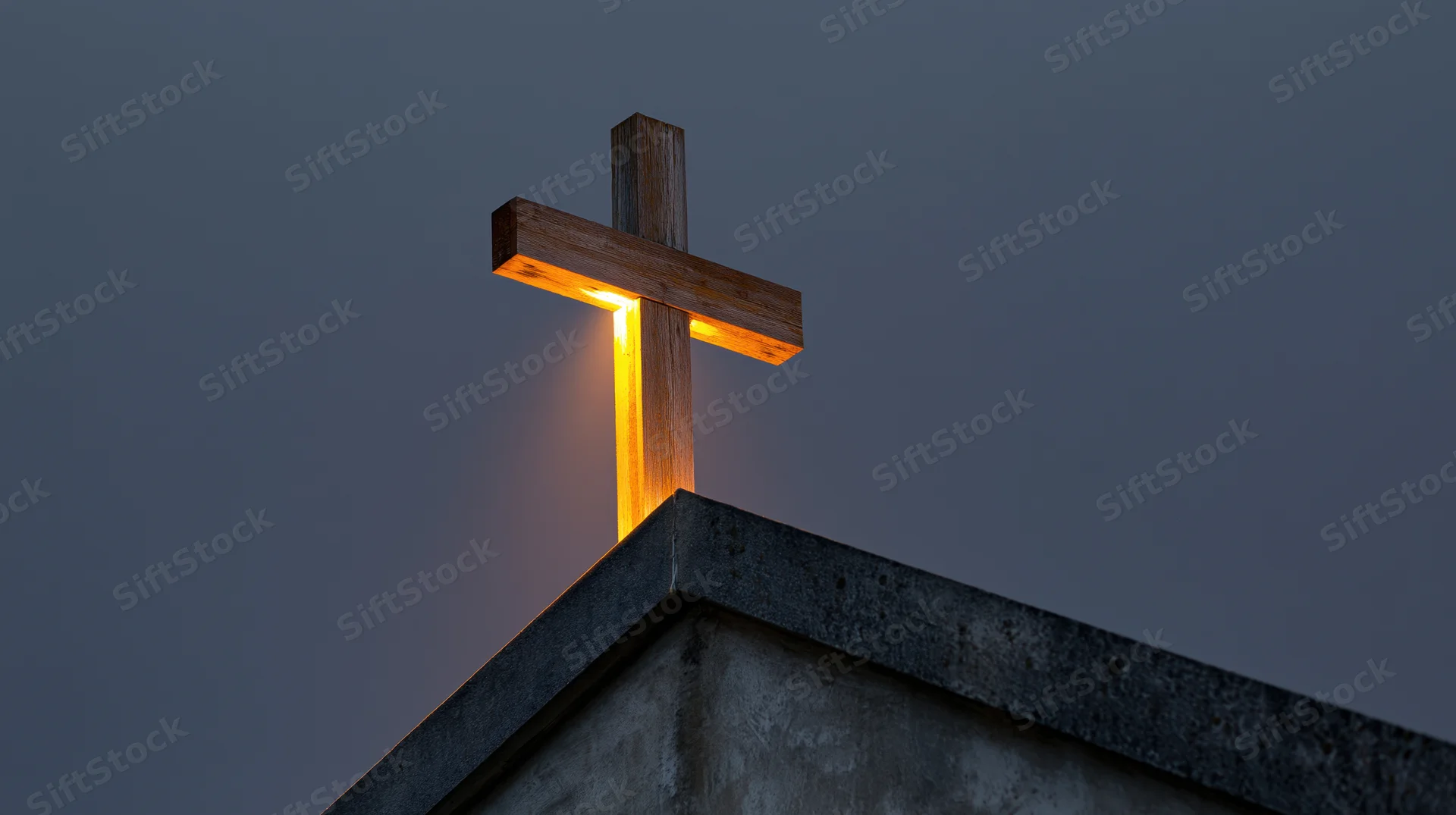 Illuminated wooden cross on church roof peak at twilight