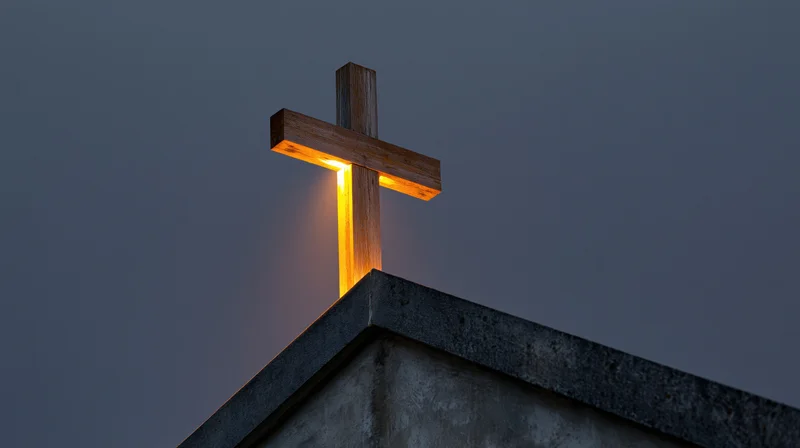 Illuminated wooden cross on church roof peak at twilight