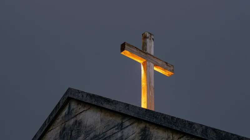 Weathered wooden cross illuminated on church roof peak at twilight