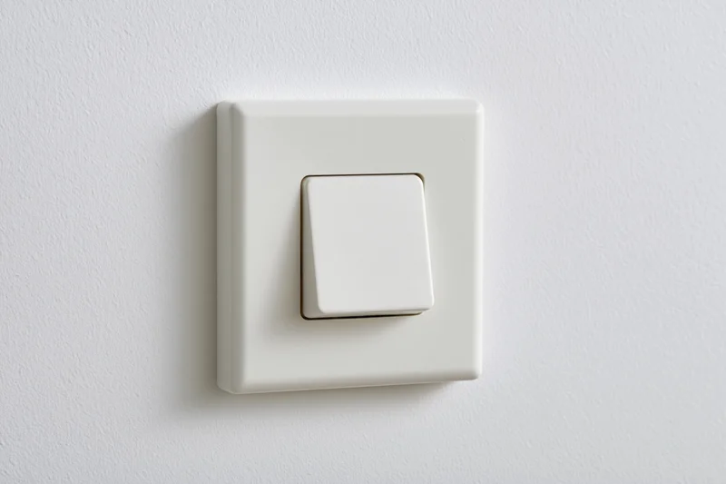 White square push-button light switch mounted on a plain white wall