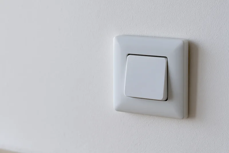White square push-button light switch mounted on a plain white wall