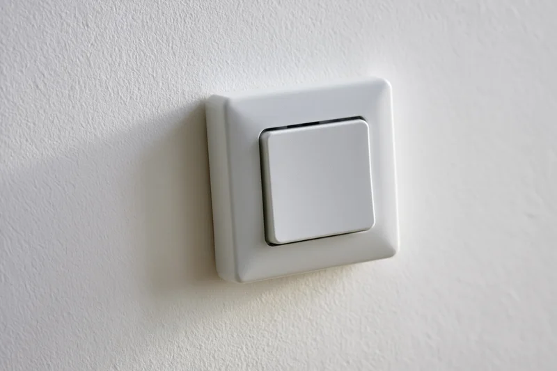 White square push-button light switch mounted on a flat white wall