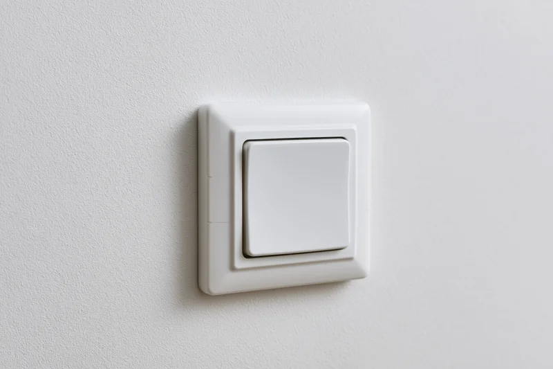 White square push-button light switch mounted on a flat white wall