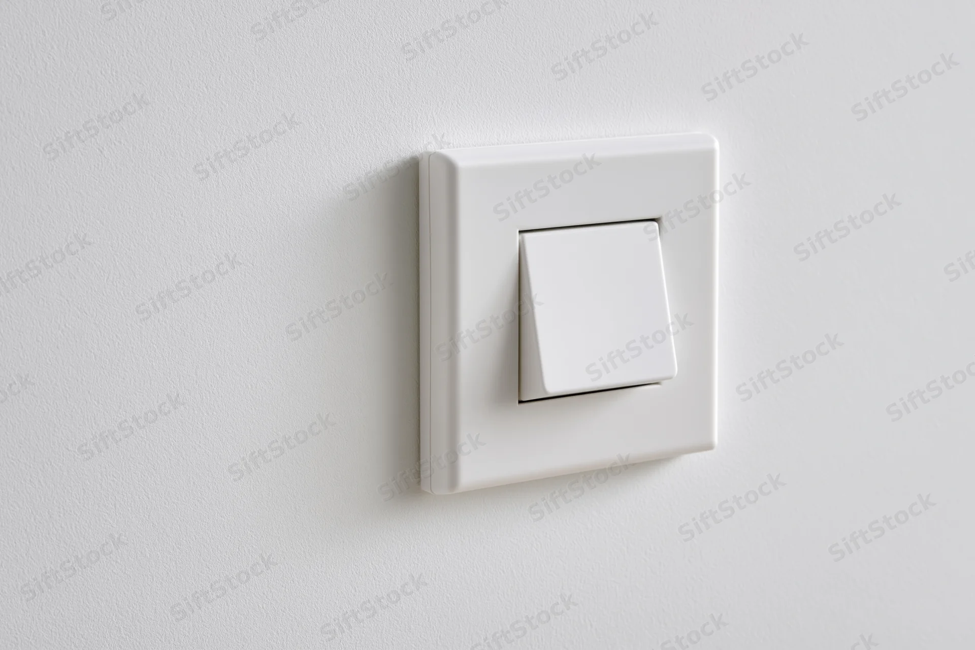 White square push-button light switch mounted on a flat white wall
