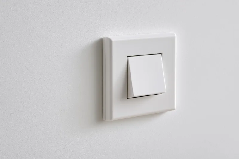 White square push-button light switch mounted on a flat white wall