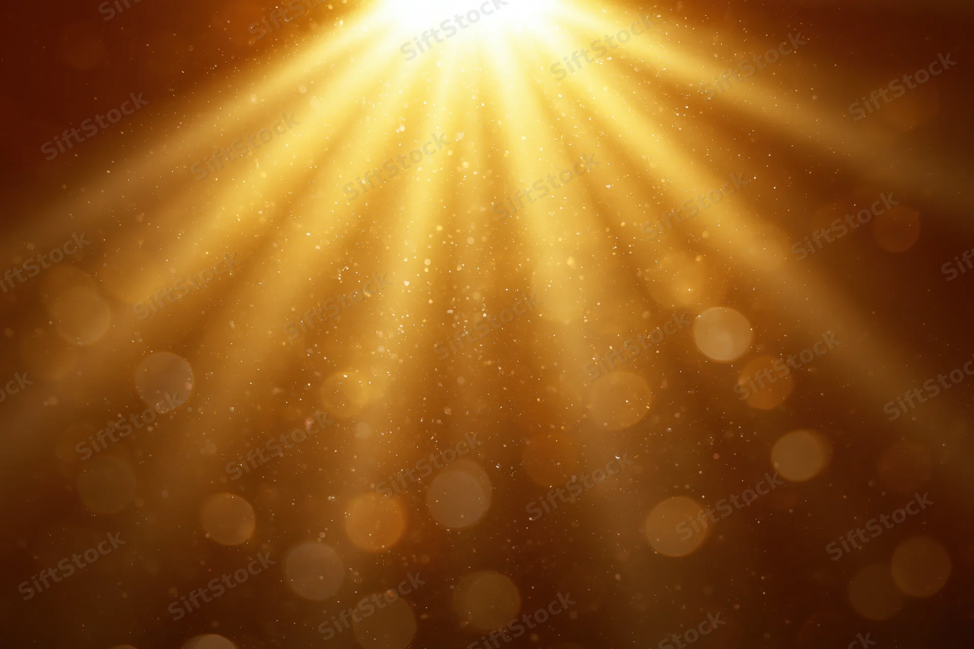 Golden light rays radiating downward with bokeh particles on abstract background