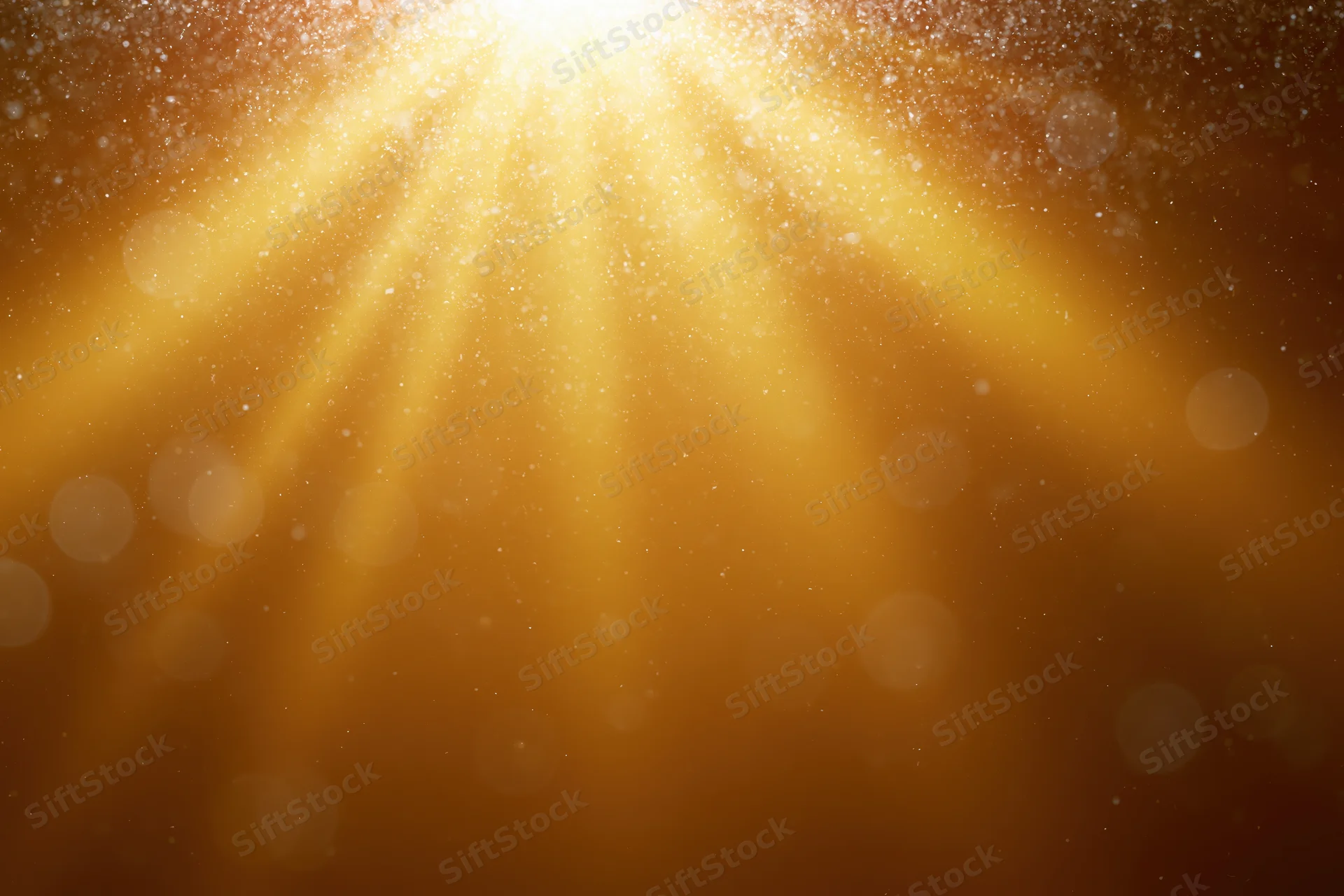 Golden light rays radiating downward through floating particles on an abstract background