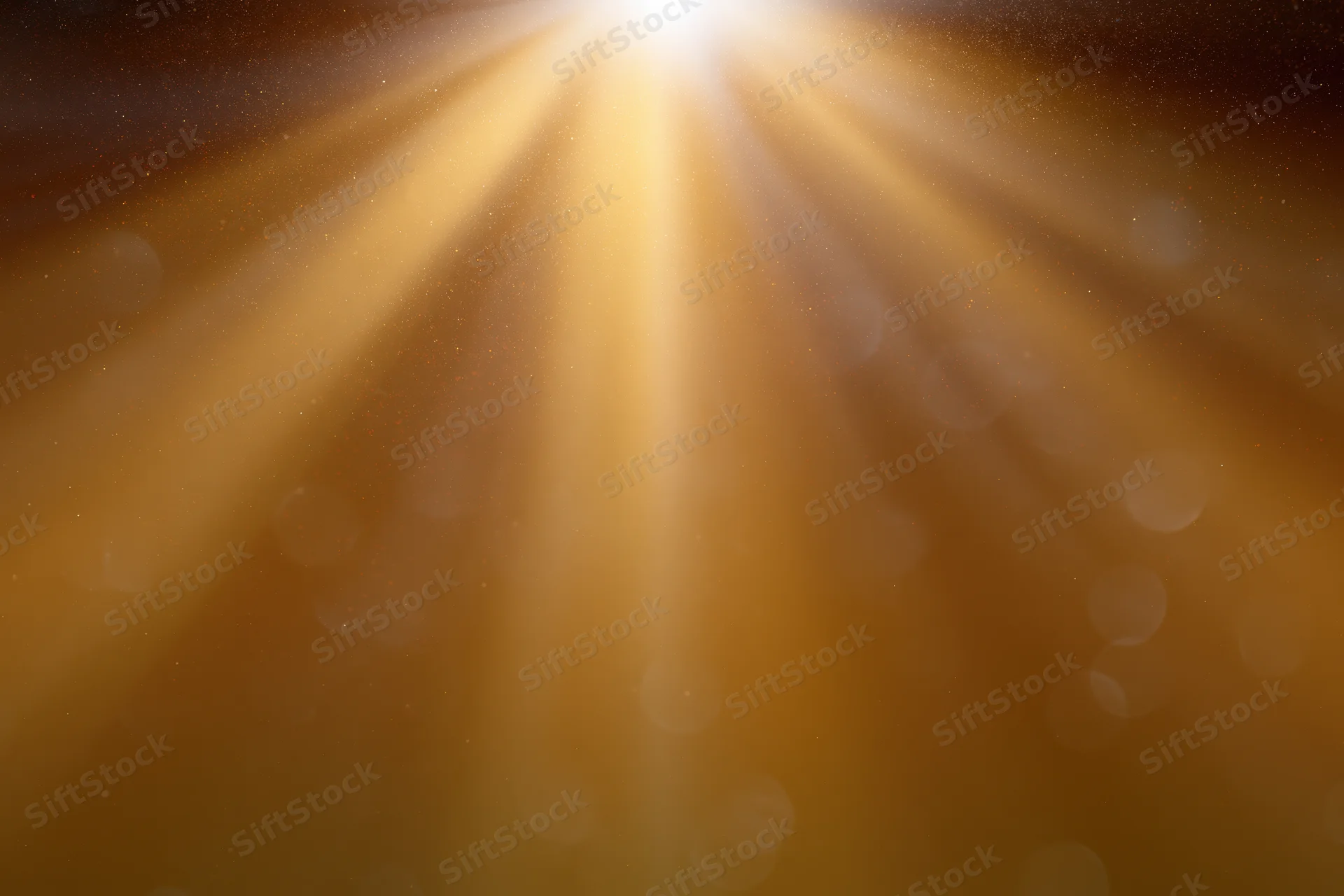Golden light rays radiating downward in an abstract background with bokeh and soft glow