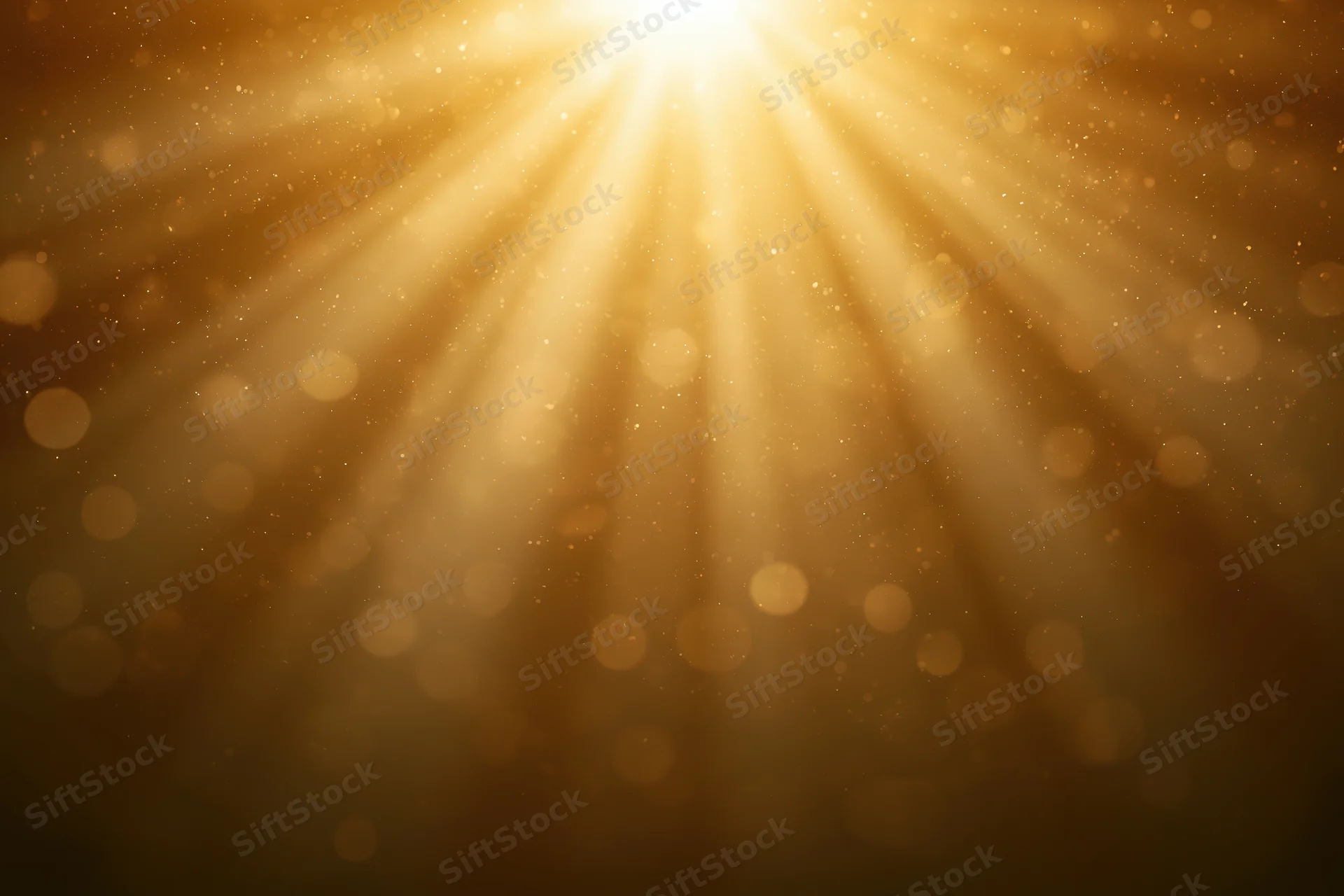 Golden light rays radiating downward with bokeh particles and soft glow in abstract background