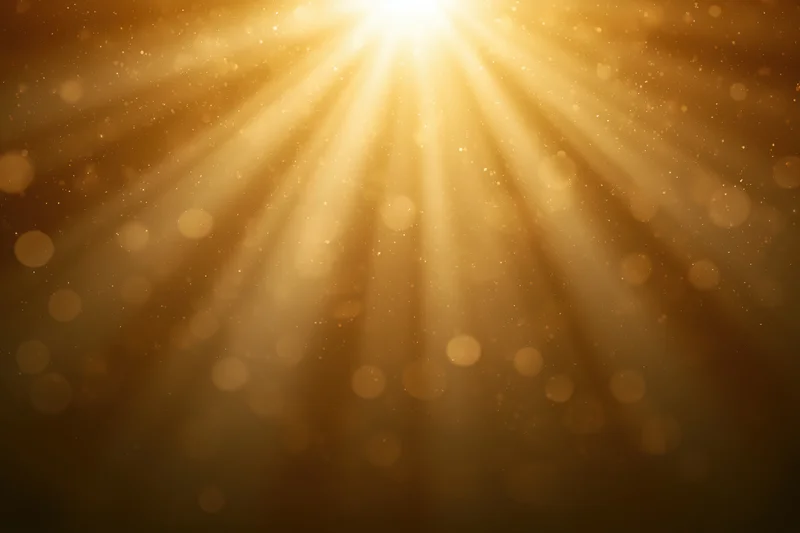 Golden light rays radiating downward with bokeh particles and soft glow in abstract background