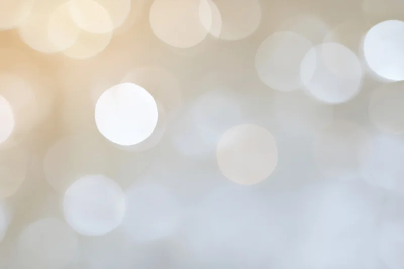 Soft out-of-focus light orbs in warm beige and white tones forming an abstract bokeh background