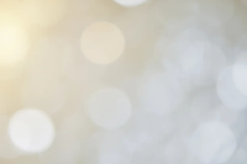 Soft out-of-focus light orbs in warm beige and white tones forming an abstract bokeh background
