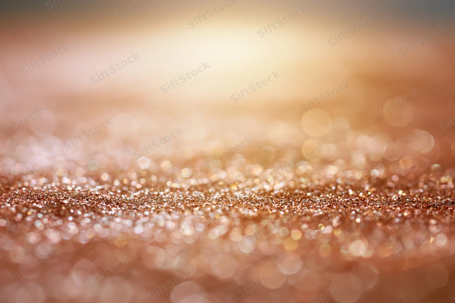 Abstract glitter texture with soft bokeh lights and warm golden sparkle across the surface