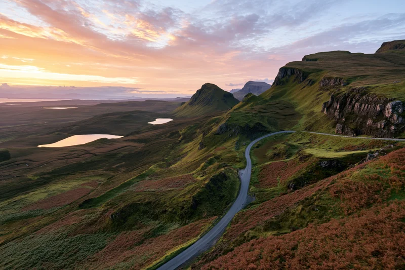 Winding single-track road through mountainous highland landscape at sunset