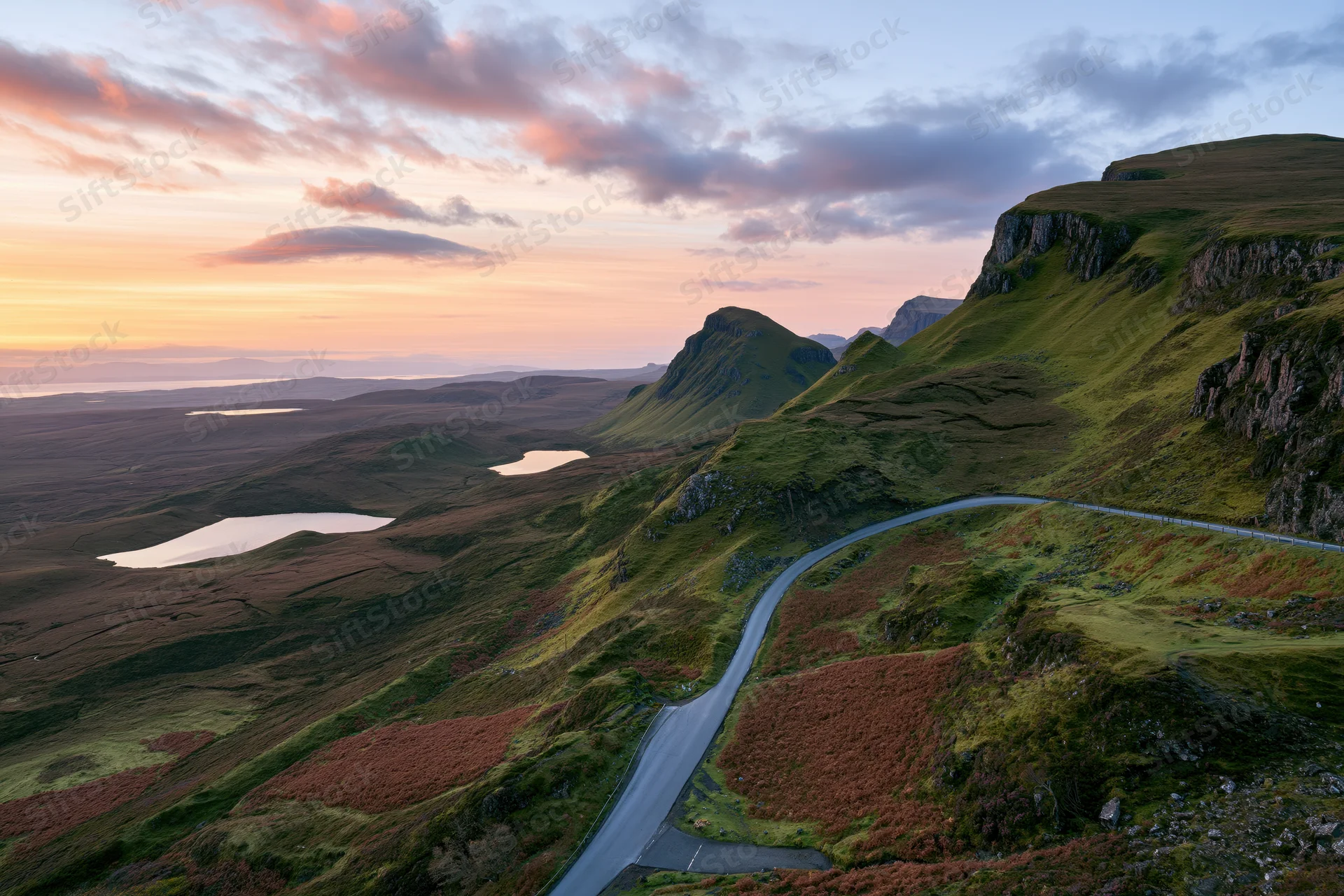 Winding single-track road through mountainous highland landscape at sunset